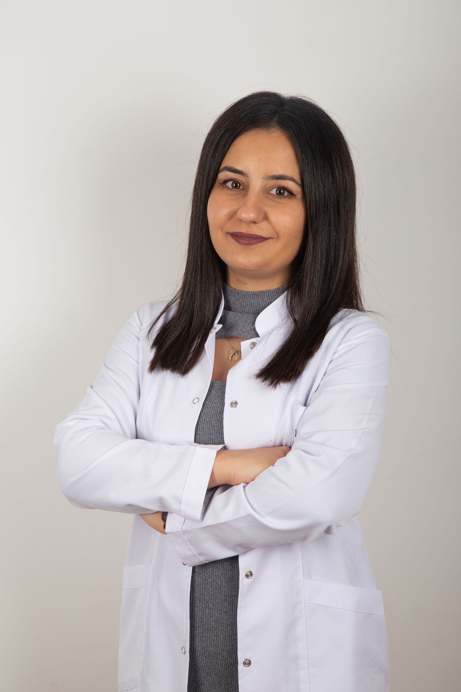 Beyaz önlüklü, gülümseyen bir kadın hekimin portresi